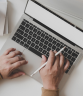 Person with a pen typing on a computer.